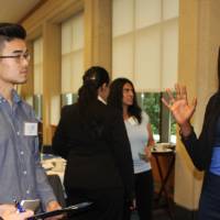 Student explaining her poster to showcase attendees